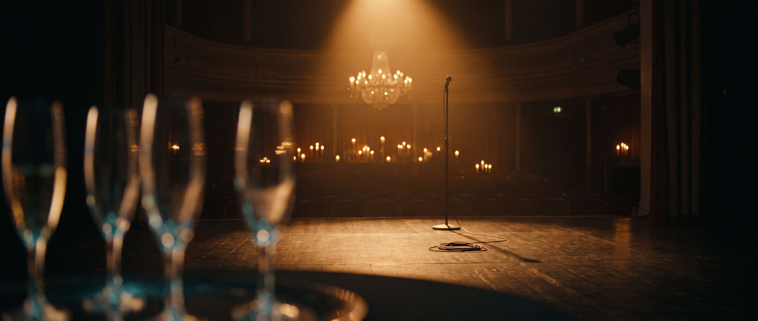 A candlelit luxury venue with a golden spotlight on an empty stage